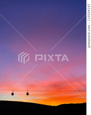 Two Gondola Cabins against Backdrop of Sunrise 110504197