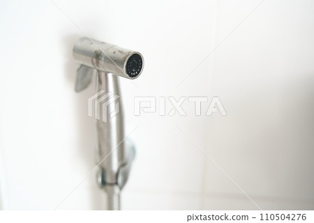 Hygiene concept. New hygienic stall shower head on the white wall background. Intimate hyg. Hygiene concept. New hygienic stall shower head on the white wall background. Intimate hyg. 110504276