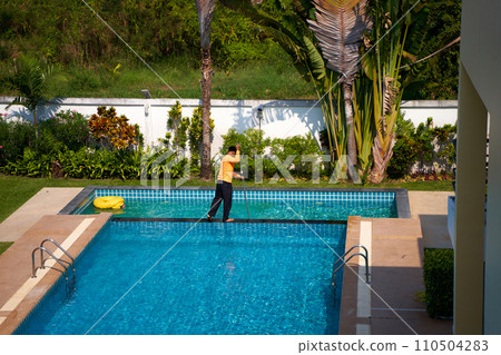 Top view of a worker cleaning a swimming pool in a private house in summer 110504283