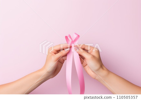 Pink ribbon held in female hands. Symbol of the fight against breast cancer 110505357