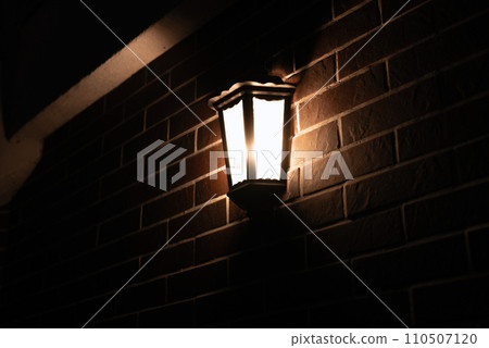 Retro-style lamp hangs on a red brick wall at night, copy space. 110507120