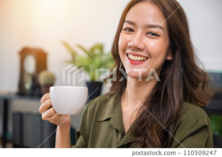Portrait of Asian young woman holding hot coffee or tea cup in morning while posing, white porcelain mug mock up, Happy beautiful woman relaxing in summer after wakeup at home, lifestyle Portrait of Asian young woman holding hot coffee or tea cup in morning while posing, white porcelain mug mock up, Happy beautiful woman relaxing in summer after wakeup at home, lifestyle 110509247