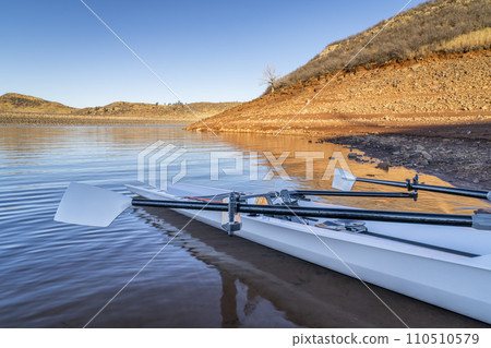 Coastal rowing shell on a shore of Horsetooth Reservoir in fall or winter scenery with a low water level. Coastal rowing shell on a shore of Horsetooth Reservoir in fall or winter scenery with a low water level. 110510579