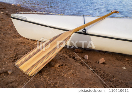 decked expedition canoe with a wooden paddle on a shore of Horsetooth Reservoir in northern Colorado 110510611