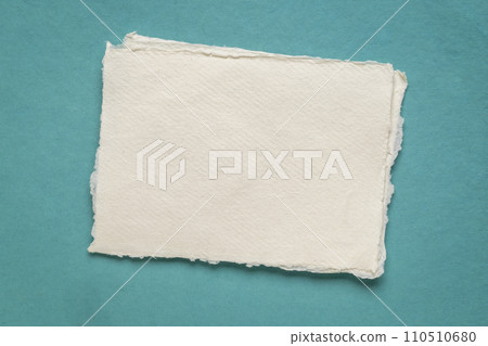 small sheet of blank white Khadi rag paper from India against blue art paper 110510680