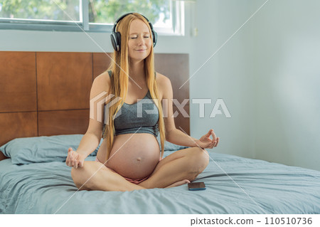 Expectant woman finds serenity in pregnancy, listening to affirmations and meditating for calmness 110510736