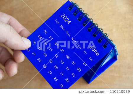 Hand showing June 2024 table calendar on wooden background. Calendar and new month concept. Hand showing June 2024 table calendar on wooden background. Calendar and new month concept. 110510989