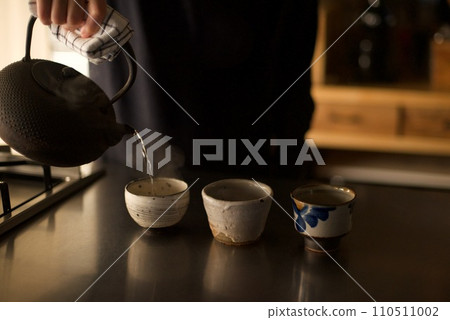 Hot water boiled in an iron kettle is being poured into a teacup 110511002