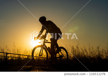 Sunset and silhouette of a person riding a road bike 110511276