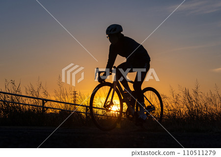 Sunset and silhouette of a person riding a road bike 110511279
