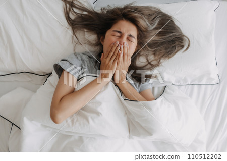 Top view of Yawning and stretching woman just wake up on the bed. 110512202