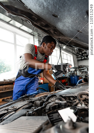 Young African male mechanic repairs car in garage close up Young African male mechanic repairs car in garage close up 110513249