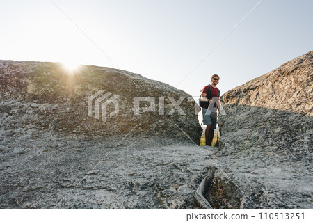Bearded traveler with a backpack and sunglasses on the top of a mountain Bearded traveler with a backpack and sunglasses on the top of a mountain 110513251