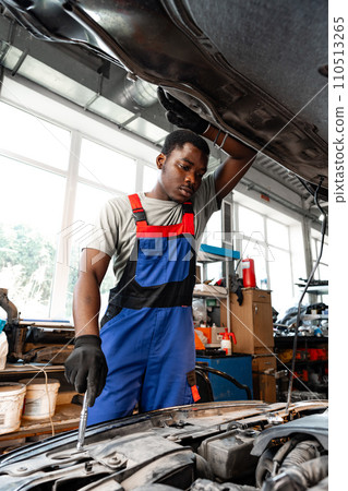 Young African male mechanic repairs car in garage close up 110513265