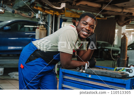 Portrait of young african man car service worker wearing uniform standing in garage 110513305