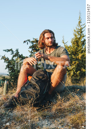 Hiker man with backpack holding thermos in his hand 110513457