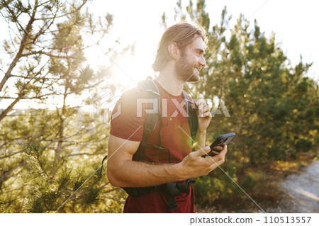 Hiker man with backpack checks the route on his phone on the walking trail 110513557