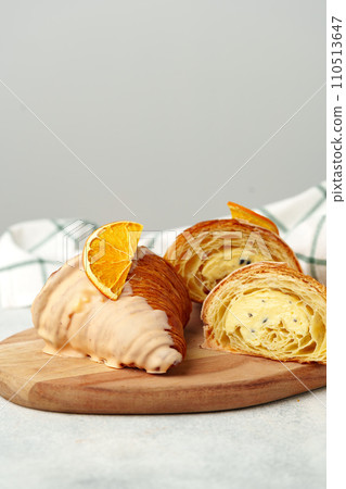 Glazed croissant with dried orange on wooden board 110513647