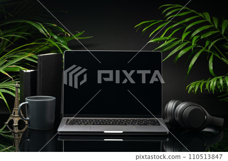 Laptop with black screen on working desk with cup and earphones on black background Laptop with black screen on working desk with cup and earphones on black background 110513847