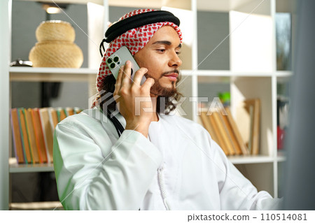 Young Arab businessman talking on the phone in the office Young Arab businessman talking on the phone in the office 110514081
