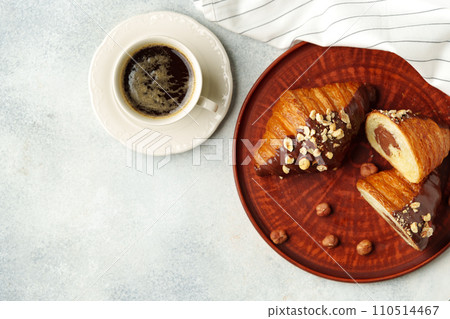 Chocolate croissant on clay plate with cup of coffee on table 110514467