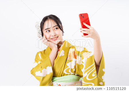 A young woman wearing furisode and using a smartphone 110515120