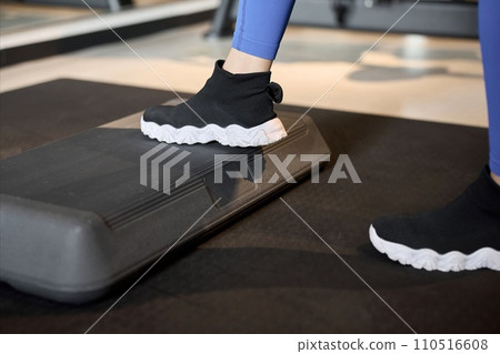 A woman training her legs on a step platform A woman training her legs on a step platform 110516608
