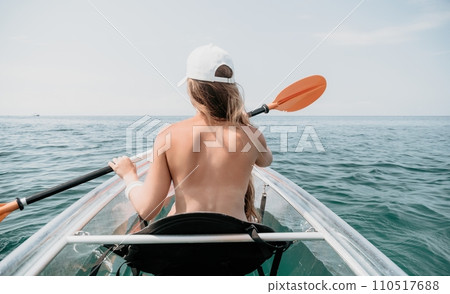 Woman in kayak back view. Happy young woman with long hair floating in transparent kayak on the crystal clear sea. Summer holiday vacation and cheerful female people relaxing having fun on the boat 110517688