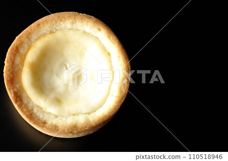 An overhead shot of a bite-sized cheese tart against a black background An overhead shot of a bite-sized cheese tart against a black background 110518946