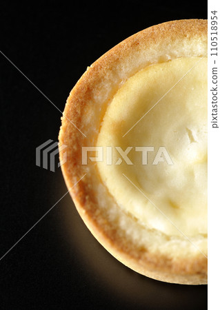 An overhead shot of a bite-sized cheese tart against a black background An overhead shot of a bite-sized cheese tart against a black background 110518954