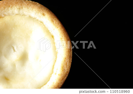 An overhead shot of a bite-sized cheese tart against a black background An overhead shot of a bite-sized cheese tart against a black background 110518960