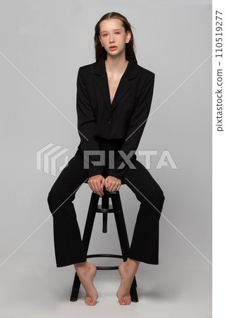 A beautiful slender girl in a black suit posing in the studio. A beautiful slender girl in a black suit posing in the studio. 110519277