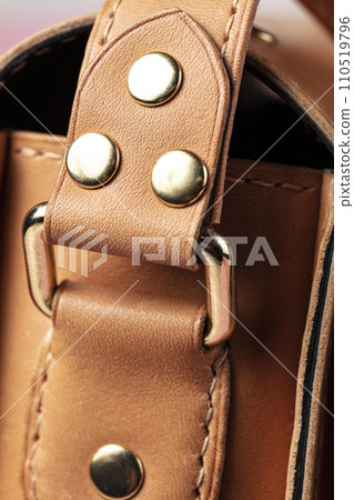 Part of a bag made of brown genuine leather with a metal fastening for the handle. 110519796