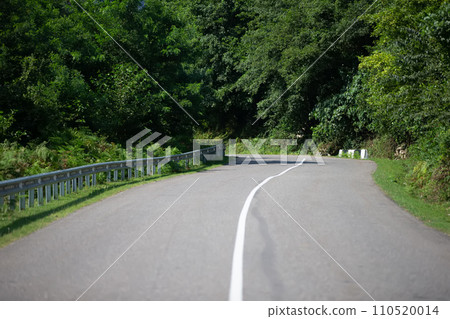 Paved road with a dividing strip along the green bushes. Paved road with a dividing strip along the green bushes. 110520014
