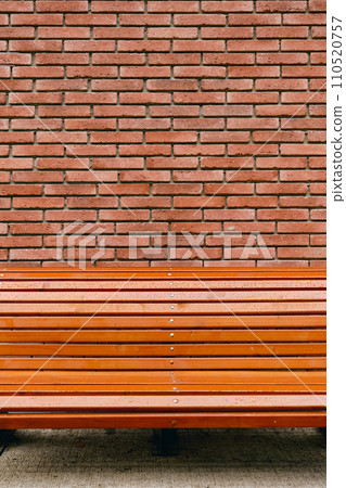 Vertical banner with bench on red-brown vintage brick wall texture background, concept for advertising on brick wall background 110520757