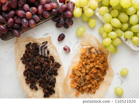 Sweet dried green and red dark raisins with ripe raw grapes on light background.Top view. Sweet dried green and red dark raisins with ripe raw grapes on light background.Top view. 110521020