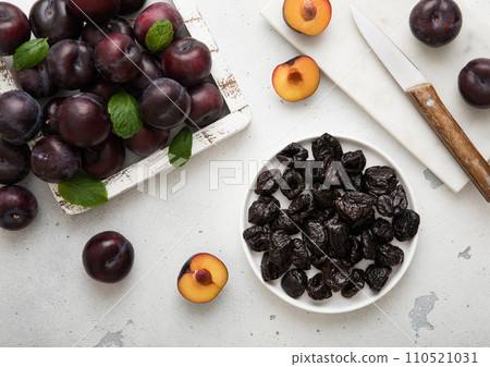 Plate with dried sweet prunes with ripe plums in wooden box on light kitchen background. 110521031