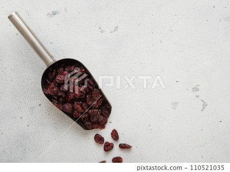Steel scoop of dried sweet and sour cranberry berry on light background. 110521035