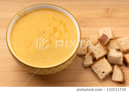 Pumpkin soup with white bread crackers on wooden table Pumpkin soup with white bread crackers on wooden table 110521726