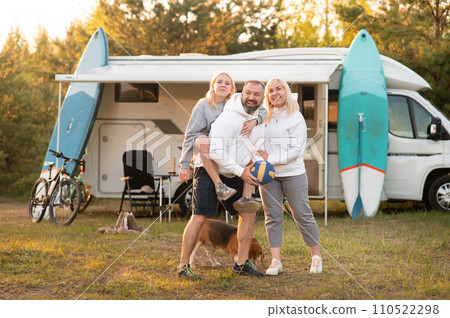 Happy parents with their child playing with a ball near their mobile home in the woods Happy parents with their child playing with a ball near their mobile home in the woods 110522298