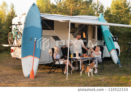 A happy family is resting nearby near their motorhome in the forest 110522310