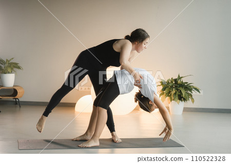 Mom and teenage daughter do gymnastics together in the fitness room. A woman and a girl train in the gym Mom and teenage daughter do gymnastics together in the fitness room. A woman and a girl train in the gym 110522328