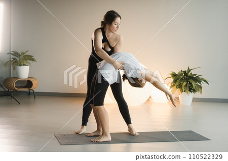Mom and teenage daughter do gymnastics together in the fitness room. A woman and a girl train in the gym 110522329