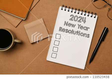 2024 New Year Resolutions Text on a spiral notebook with cup of coffee and glasses. 2024 New Year Resolutions Text on a spiral notebook with cup of coffee and glasses. 110523438