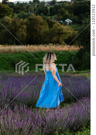 a girl in a blue long sundress on a lavender field. 110523912