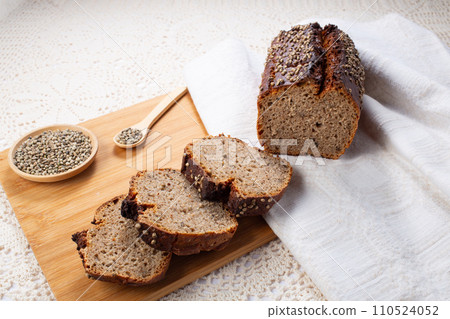 Sliced dark rye hemp seed bread on wooden board on linen towel. Healthy pastry Sliced dark rye hemp seed bread on wooden board on linen towel. Healthy pastry 110524052