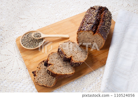 Fresh baked loaf of spelt sourdough bread with hemp seeds is on linen towel. Healthy pastry 110524056