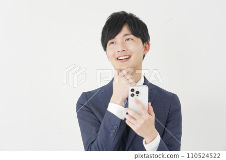 A businessman imagining with a smartphone, white background A businessman imagining with a smartphone, white background 110524522