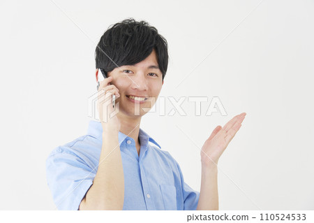 A man pointing to the right side with his palm while talking on a smartphone, white background 110524533
