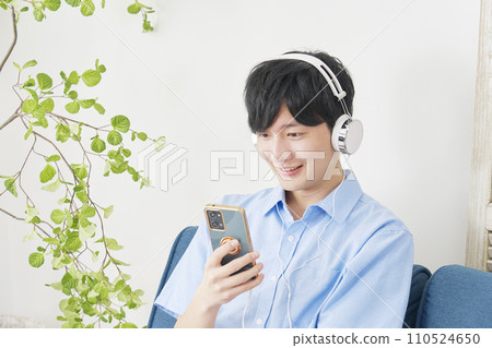 Man listening to music on smartphone at home 110524650